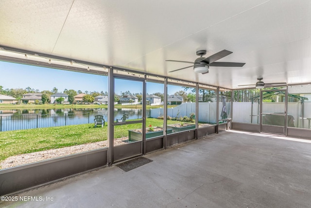 unfurnished sunroom with a ceiling fan and a water view