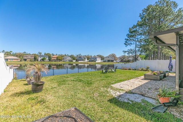 view of yard featuring a water view, a fenced backyard, and a garden