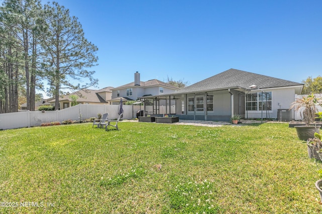 rear view of property with a yard, central AC unit, a fenced backyard, and a sunroom