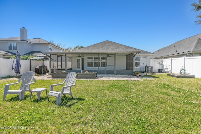 rear view of house with a lawn, a fenced backyard, and a sunroom