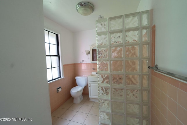 bathroom featuring a wainscoted wall, toilet, tile walls, and tile patterned flooring