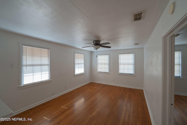 unfurnished room with wood finished floors, visible vents, a wealth of natural light, and ceiling fan