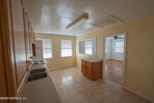 kitchen with light countertops, light tile patterned floors, visible vents, and a sink