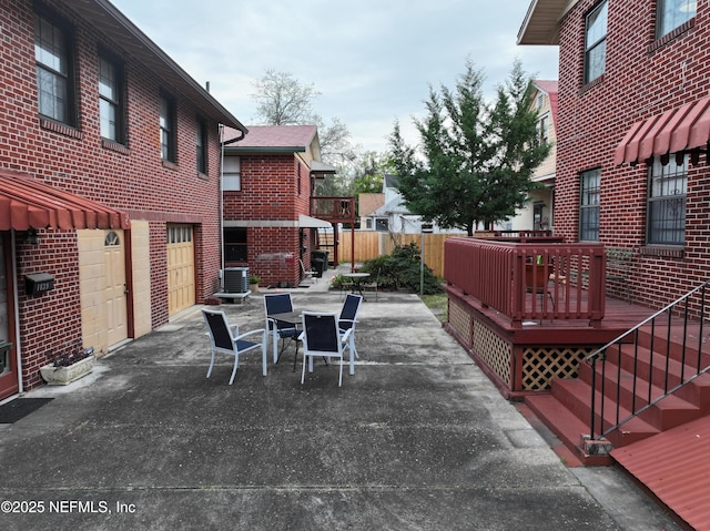 view of patio / terrace featuring fence, outdoor dining area, an attached garage, a deck, and central air condition unit