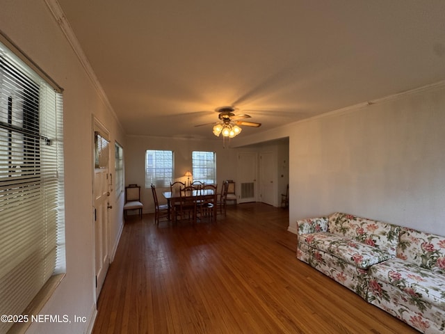 unfurnished dining area featuring visible vents, a ceiling fan, wood finished floors, crown molding, and baseboards