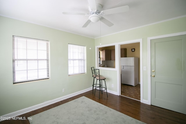 unfurnished room with ornamental molding, baseboards, dark wood-style flooring, and ceiling fan