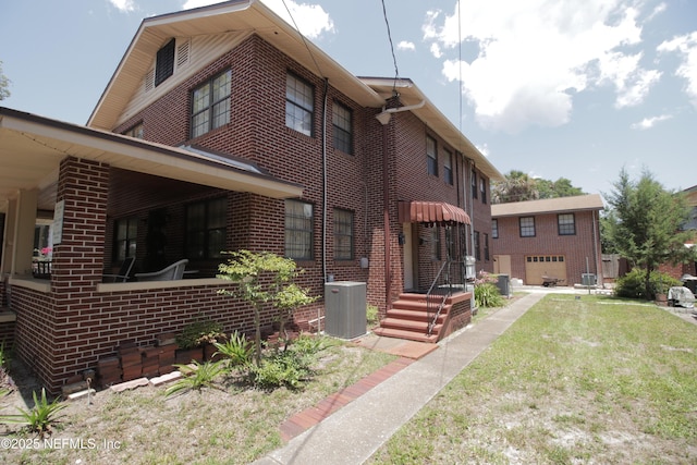 view of front of property with brick siding, central air condition unit, and a front yard