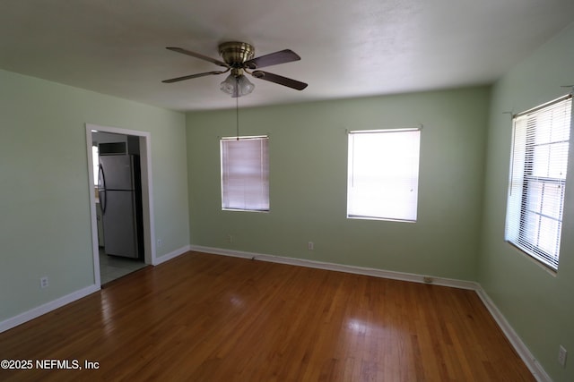 unfurnished bedroom featuring baseboards, wood finished floors, a ceiling fan, and freestanding refrigerator