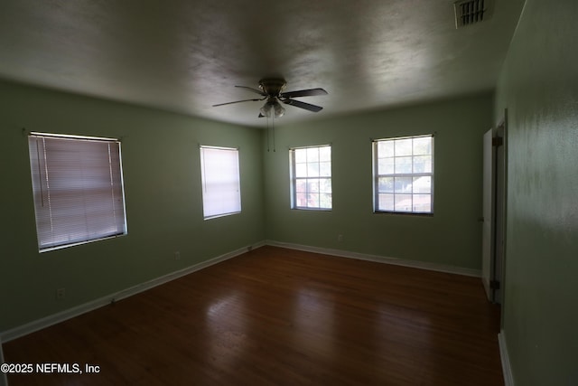 spare room featuring visible vents, baseboards, ceiling fan, and wood finished floors