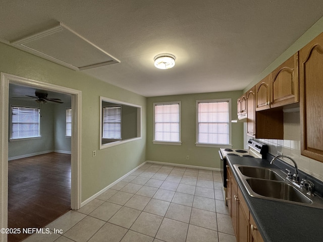 kitchen featuring a sink, dark countertops, electric range oven, light tile patterned floors, and baseboards