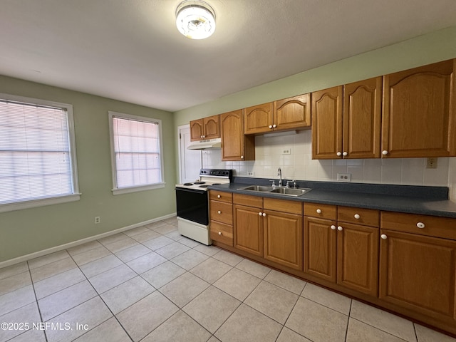 kitchen featuring electric range, brown cabinetry, tasteful backsplash, and a sink