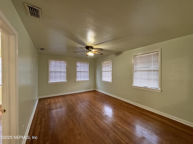 spare room with visible vents, baseboards, dark wood-type flooring, and ceiling fan