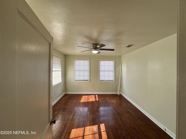 unfurnished room with visible vents, plenty of natural light, wood finished floors, and a ceiling fan