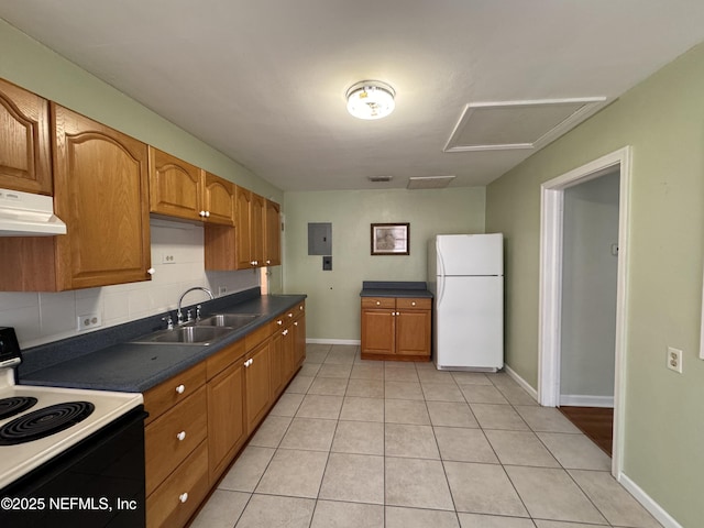 kitchen featuring tasteful backsplash, under cabinet range hood, range with electric stovetop, freestanding refrigerator, and a sink