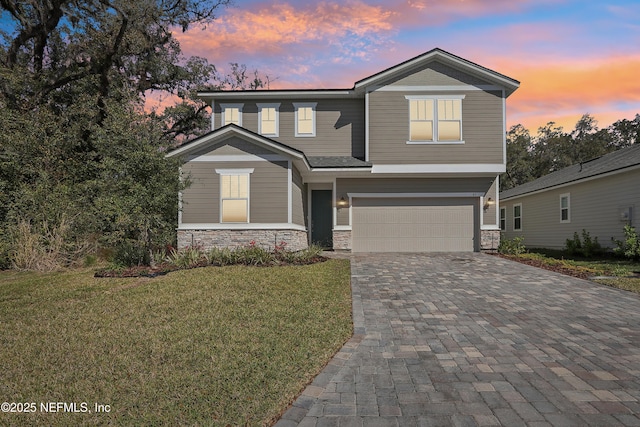 view of front facade featuring decorative driveway, stone siding, a front lawn, and an attached garage