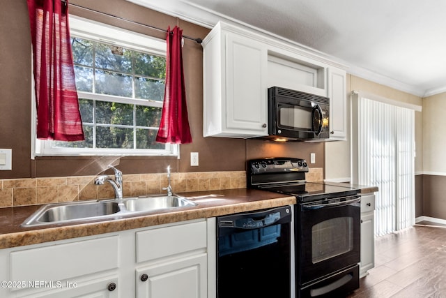 kitchen with black appliances, a sink, wood finished floors, white cabinets, and crown molding