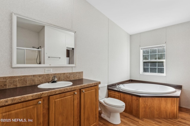 full bath featuring a shower stall, toilet, a garden tub, wood finished floors, and vanity