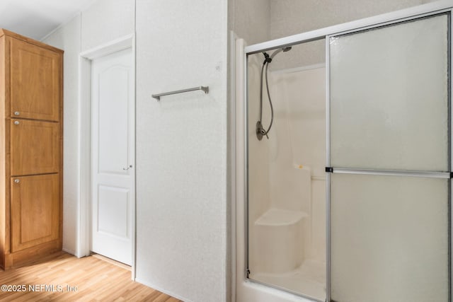 bathroom with wood finished floors and a shower with door