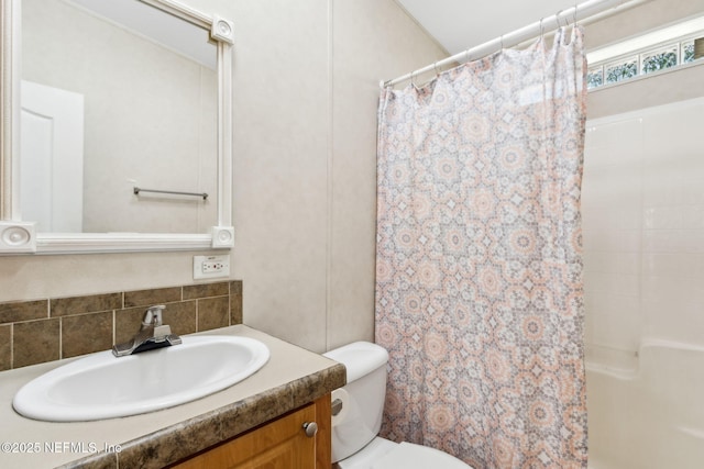 bathroom featuring vanity, toilet, and tasteful backsplash