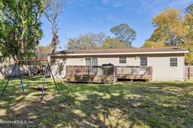 rear view of house featuring a deck, a playground, fence, and a lawn