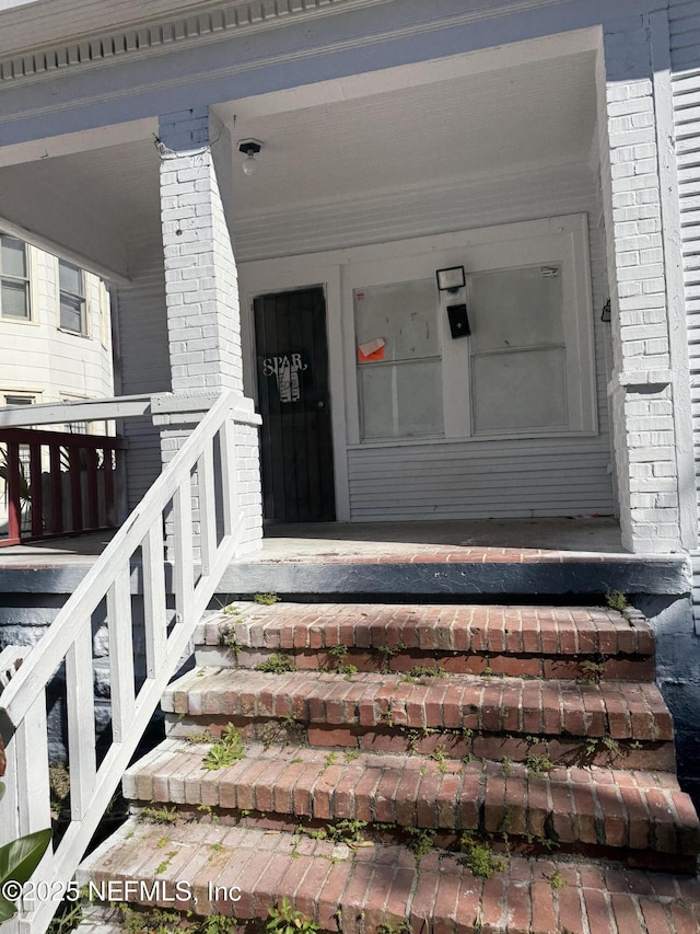 property entrance with brick siding and a porch