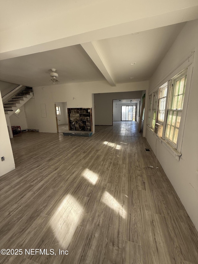 unfurnished living room featuring visible vents, ceiling fan, stairway, a fireplace, and wood finished floors