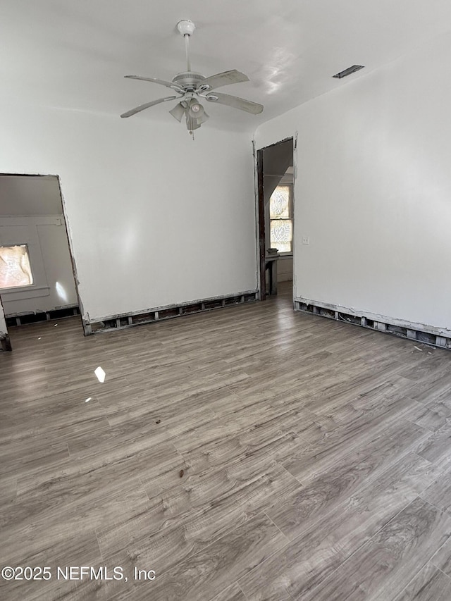 empty room featuring visible vents, wood finished floors, and a ceiling fan