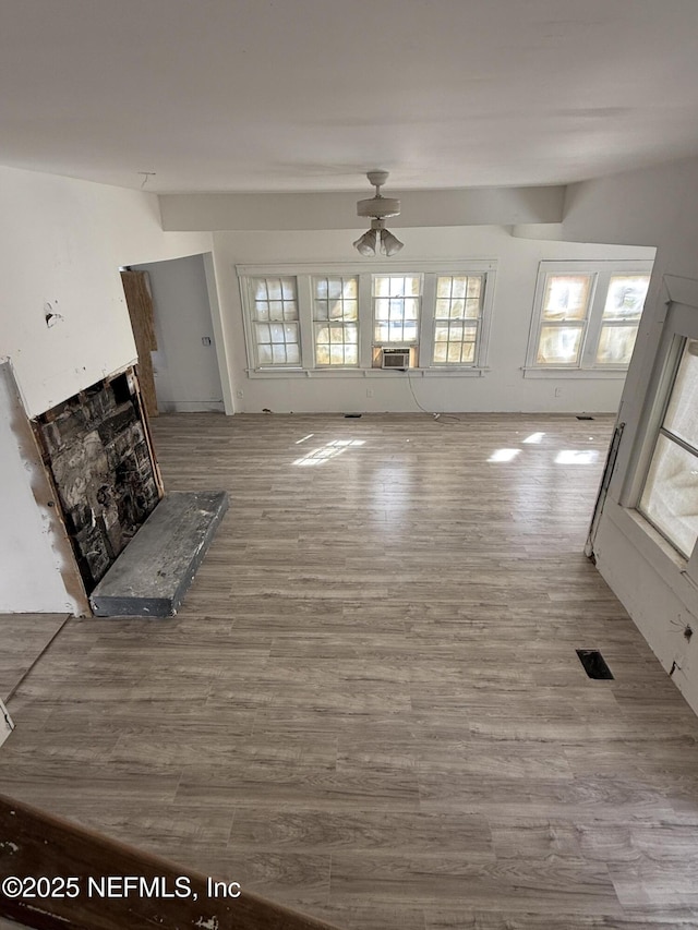 unfurnished living room with visible vents, wood finished floors, a high end fireplace, cooling unit, and ceiling fan