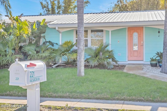 view of front of property featuring metal roof and a front lawn