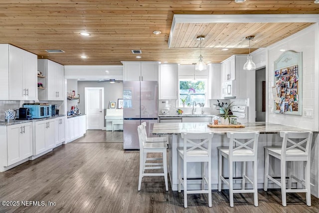 kitchen featuring white microwave, dark wood-type flooring, wood ceiling, freestanding refrigerator, and open shelves