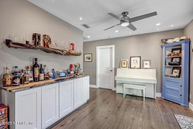 bar with wood finished floors, visible vents, recessed lighting, ceiling fan, and indoor bar