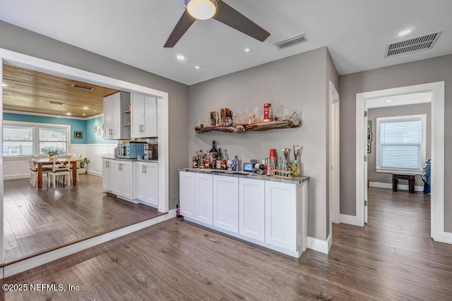 bar featuring a healthy amount of sunlight, wood finished floors, visible vents, and ceiling fan