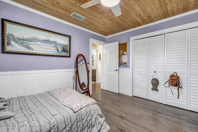 bedroom with wooden ceiling, crown molding, and a wainscoted wall