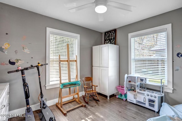 playroom with plenty of natural light, baseboards, light wood-type flooring, and a ceiling fan