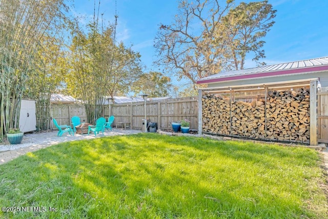 view of yard with a patio area, a fenced backyard, and an outdoor fire pit