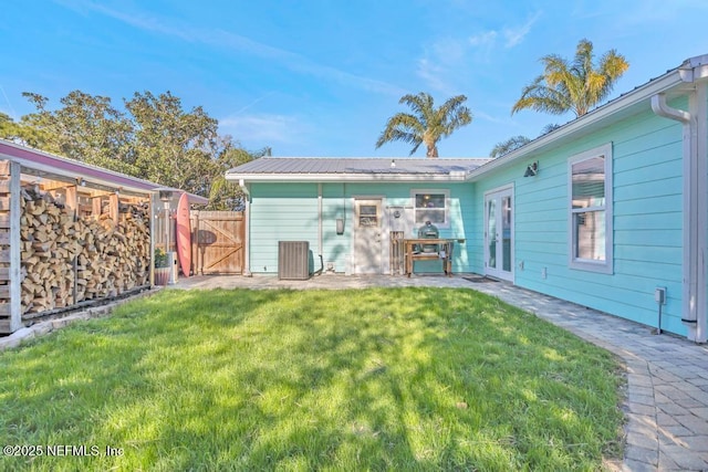 rear view of house with fence, metal roof, a yard, a patio, and a gate