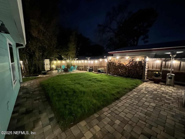 yard at twilight featuring a patio and a fenced backyard