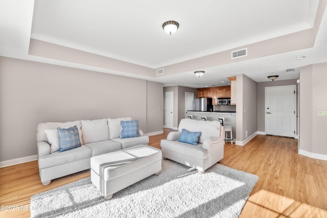 living area featuring light wood-type flooring, visible vents, and baseboards