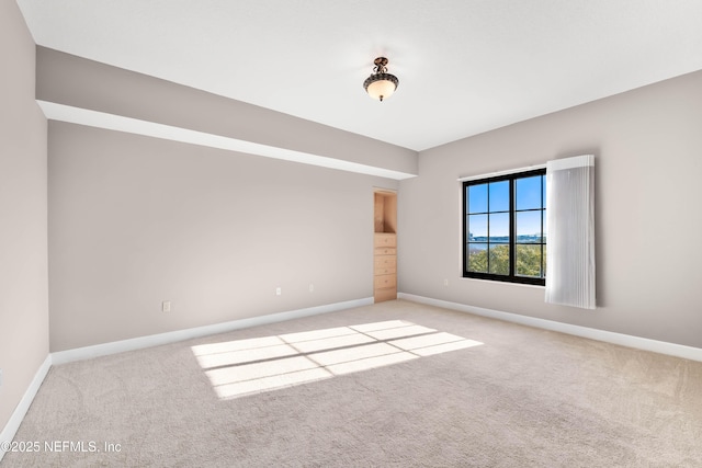 carpeted spare room featuring baseboards