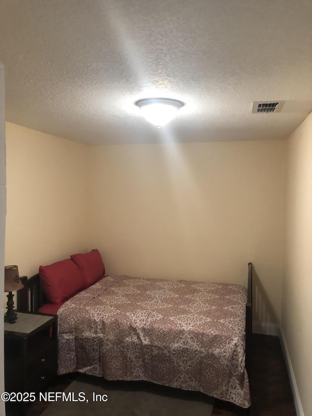 bedroom featuring visible vents, a textured ceiling, and baseboards