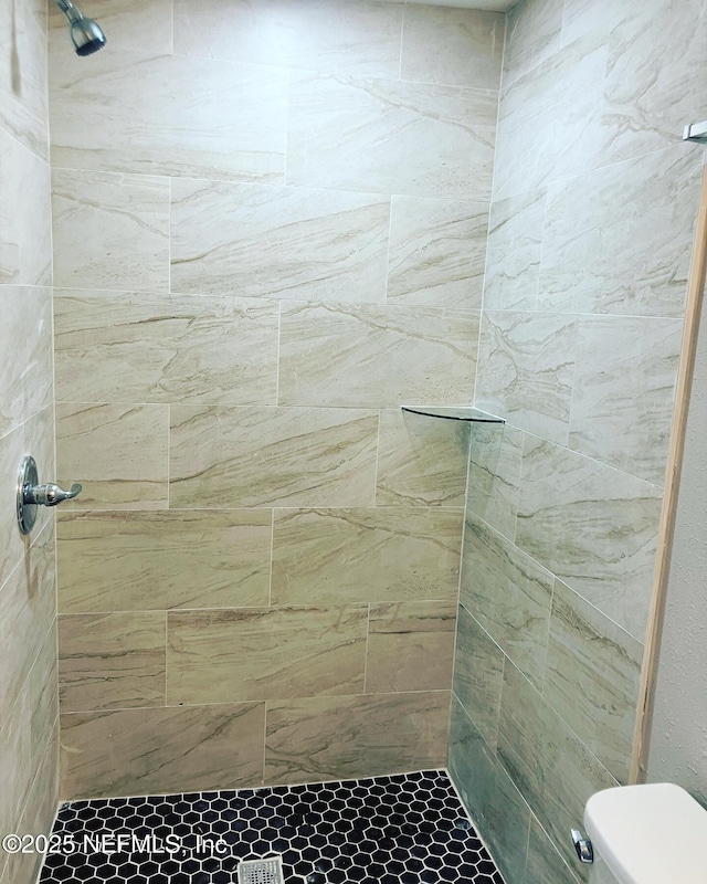 bathroom with a tile shower and toilet