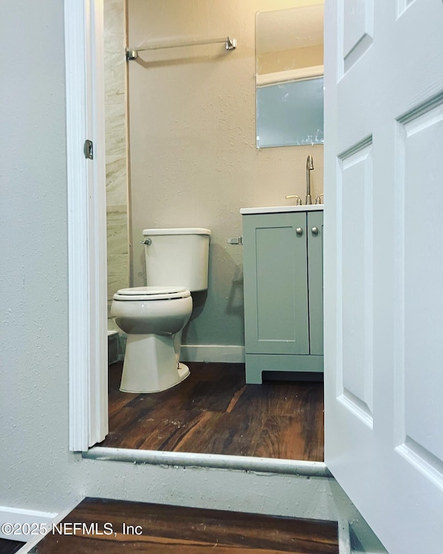 bathroom featuring toilet, vanity, baseboards, and wood finished floors