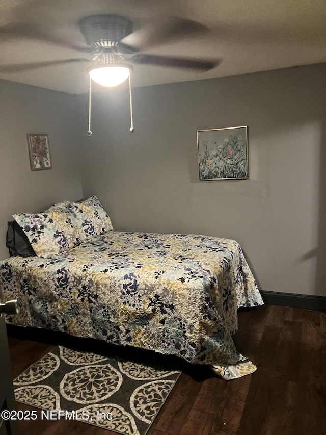 bedroom with baseboards, dark wood-type flooring, and a ceiling fan