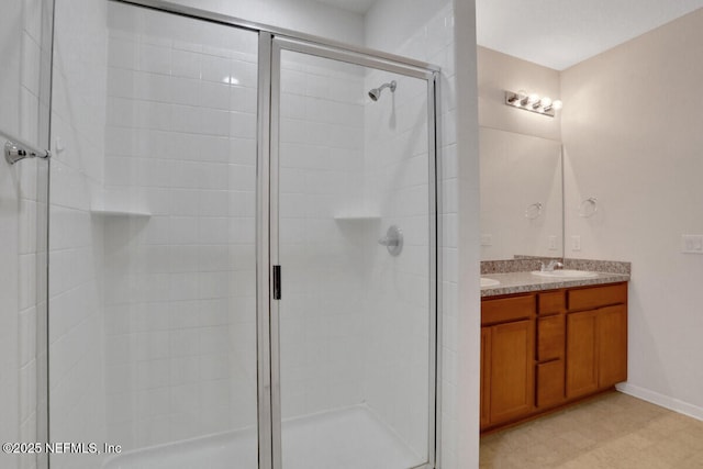 bathroom featuring double vanity, baseboards, a stall shower, and a sink