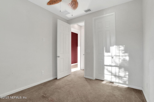 empty room featuring visible vents, carpet floors, and baseboards