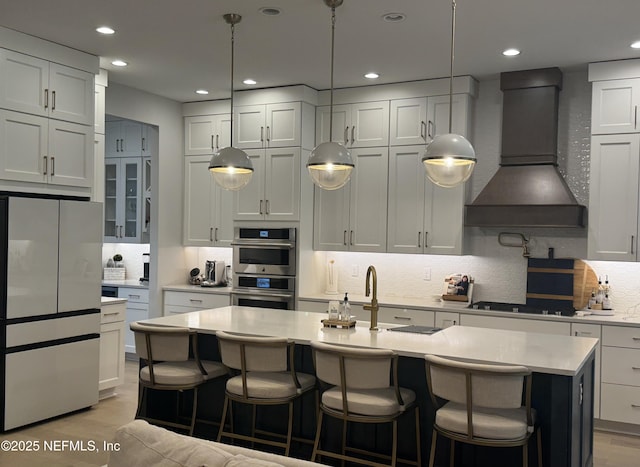 kitchen featuring light countertops, decorative backsplash, freestanding refrigerator, custom exhaust hood, and gas cooktop