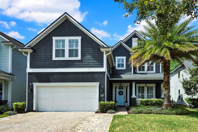 view of front facade with an attached garage, a front lawn, and decorative driveway