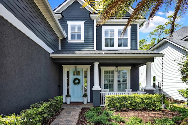 property entrance with covered porch and stucco siding