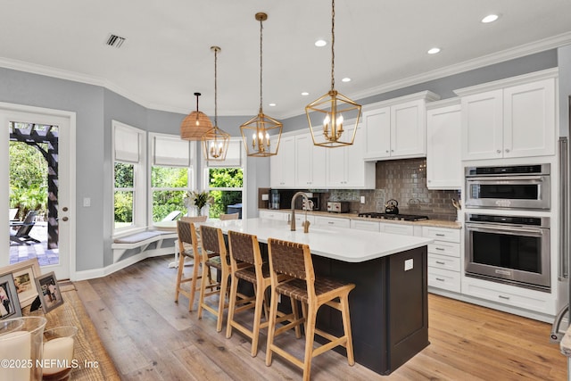 kitchen featuring decorative backsplash, light countertops, plenty of natural light, appliances with stainless steel finishes, and a notable chandelier