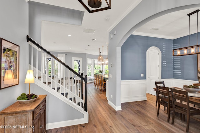 interior space with arched walkways, wood finished floors, and crown molding